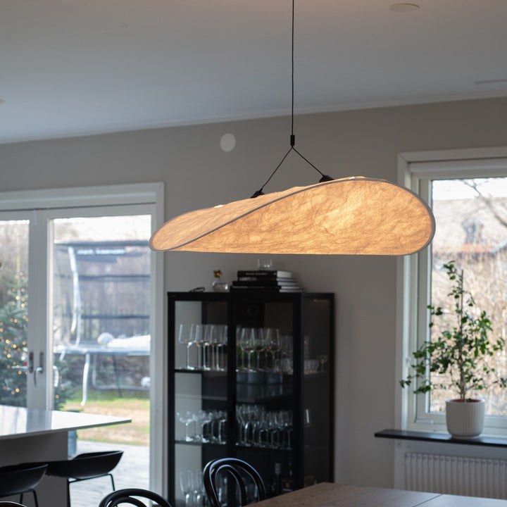 Sailing taklampa med organisk form i ljus ton, hängande ovanför matbord i stilrent skandinaviskt hem med mjuka naturmaterial.