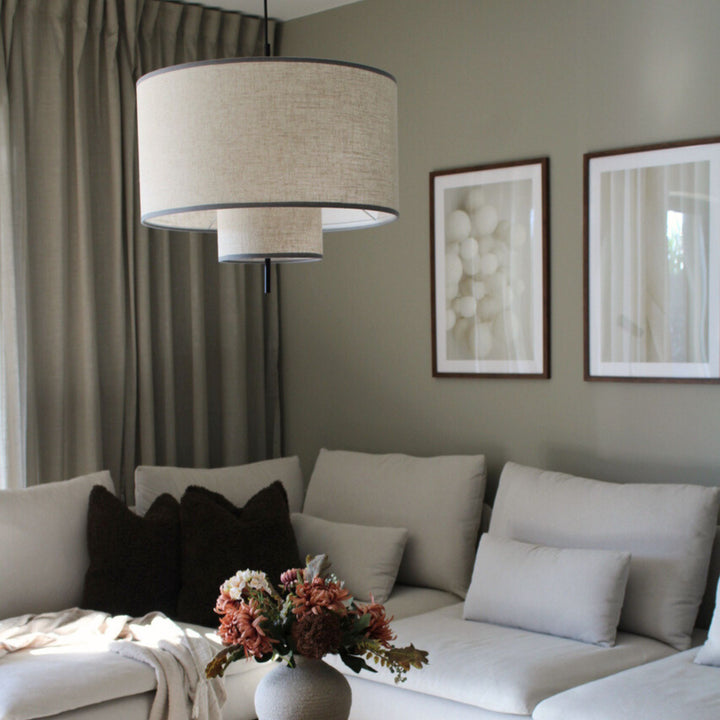 Tambour taklampa i textil med stilren cylindrisk form, placerad ovanför soffbord i ljust vardagsrum med skandinavisk inredning.