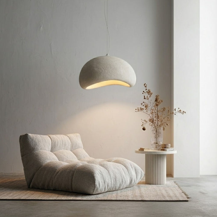 Wabi Sabi Arch 60cm taklampa - mjuk organisk form hängande över loungefåtölj i en lugn och minimalistisk skandinavisk miljö.