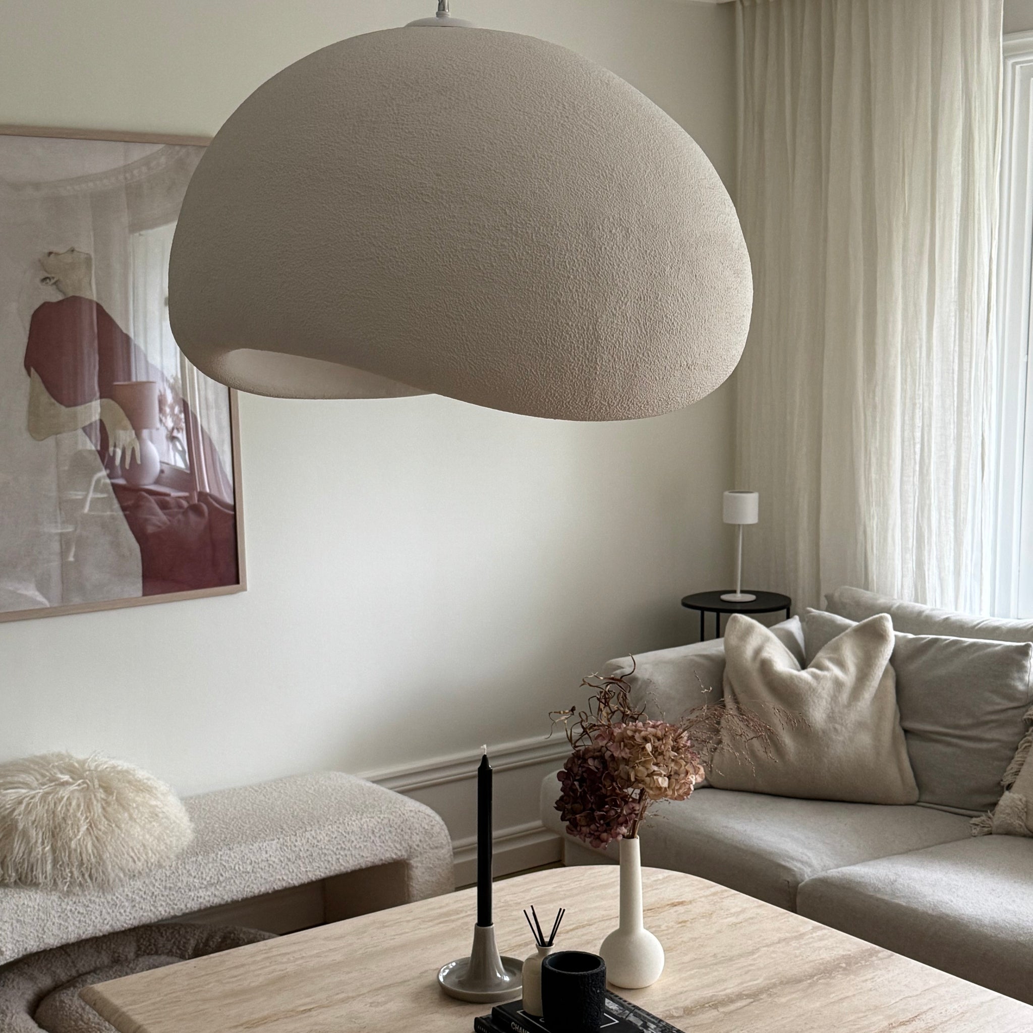 Wabi Sabi Arch taklampa i beige med organisk form ovanför soffbord i stilrent skandinaviskt vardagsrum